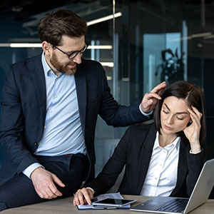 Man's hand on colleague's shoulder, representing inappropriate physical contact and workplace harassment in San Bernardino County, CA.